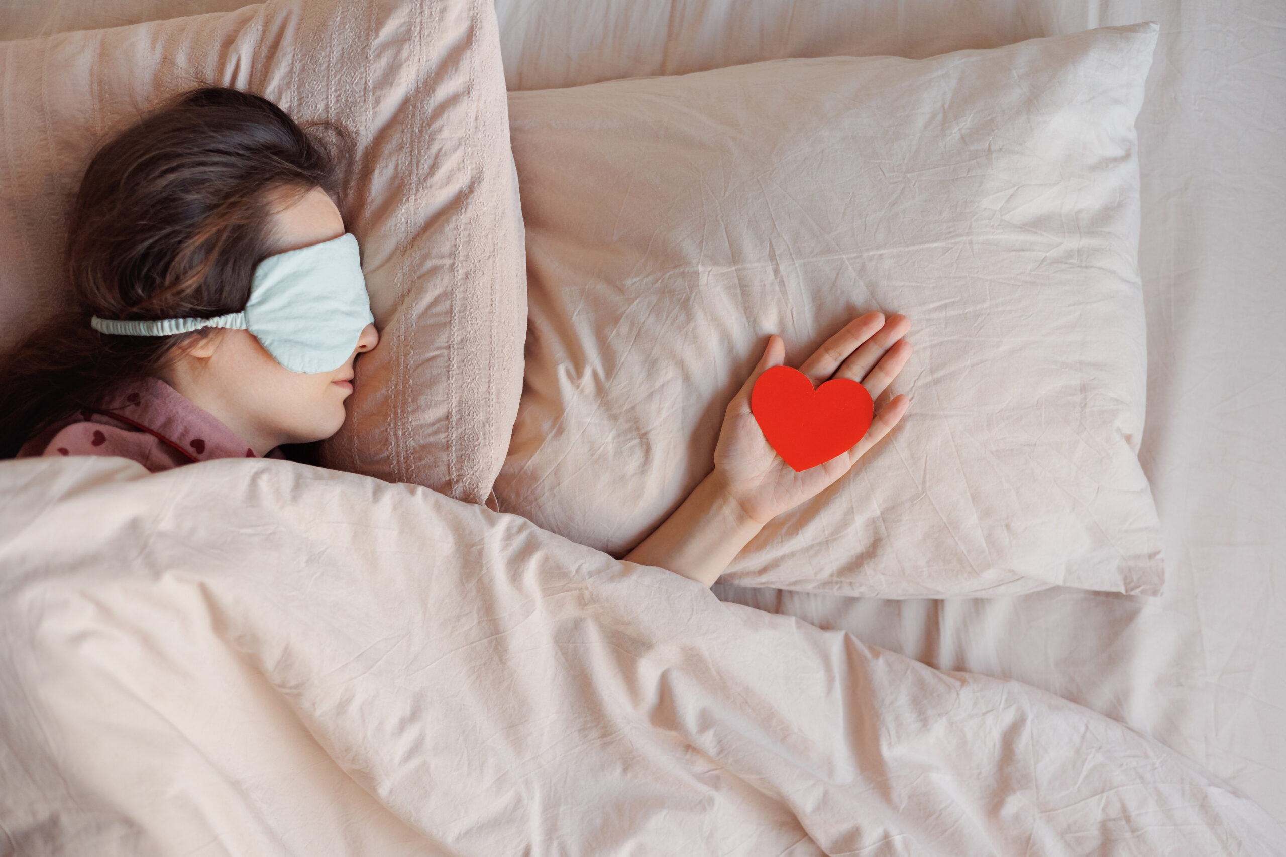 person in bed wearing sleep mask on morning of February 14, Valentine's Day
